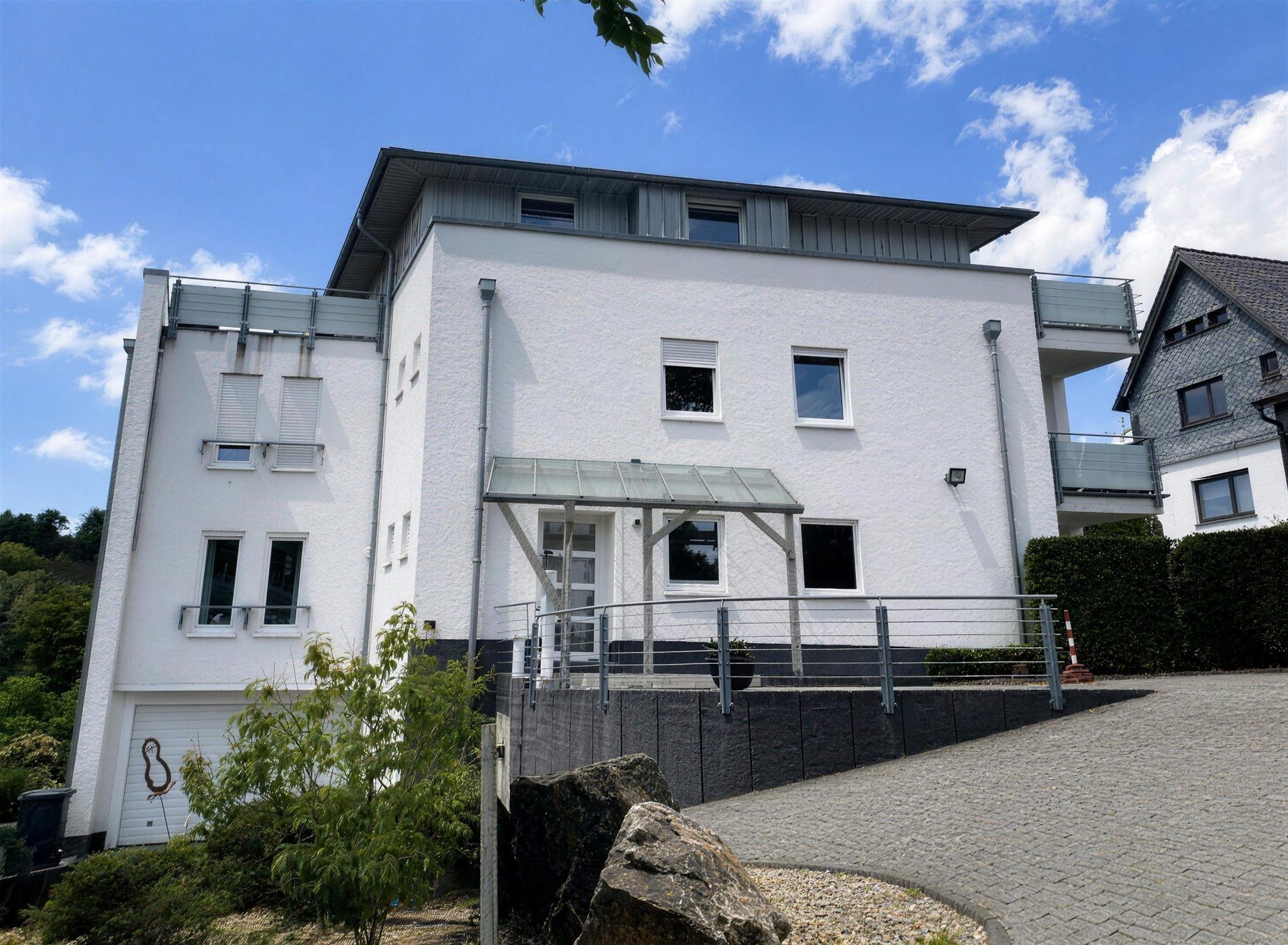 Weißes Wohnhaus mit Glasvordach am Hang, daran sechs Punkte, die in eine Bewertung einfließen